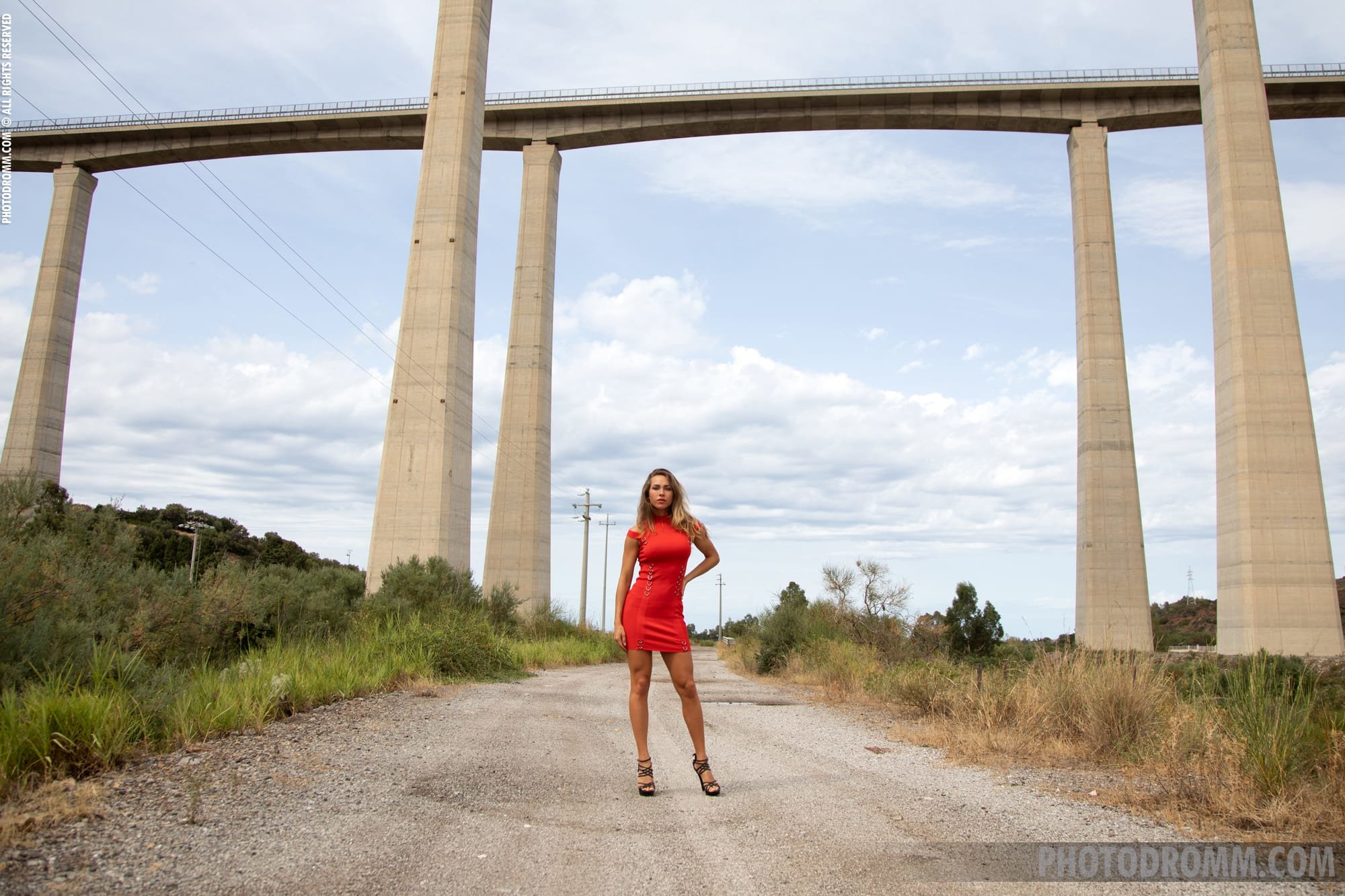 Busty Goldie drops off her sexy red dress under a huge viaduct