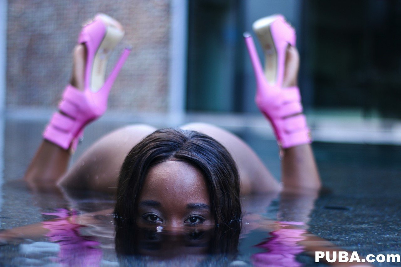 Black girl Ashley Pink exposes her bare ass as she emerges from a pool