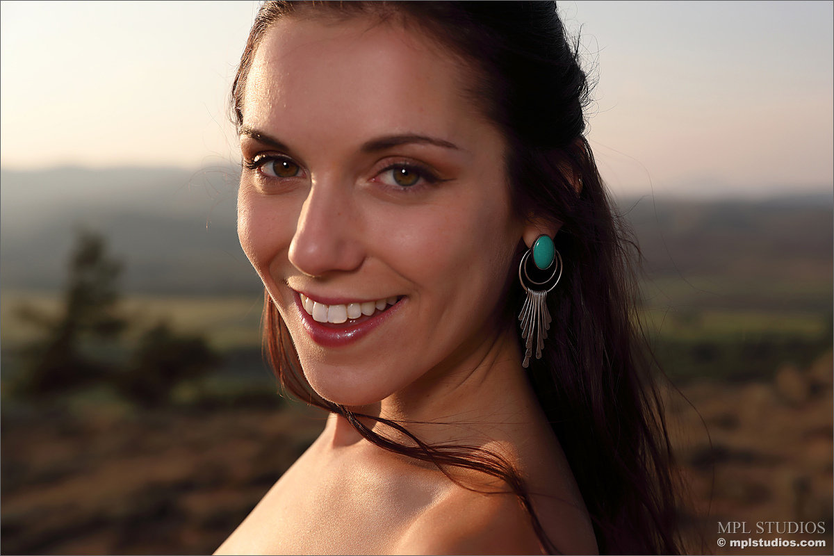 Solo girl wears her hair in pigtails while getting naked on scrubby terrain