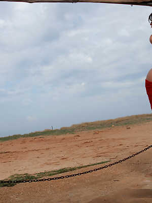 Ella Mai posing outdoor near beach with red scarf and on high heels