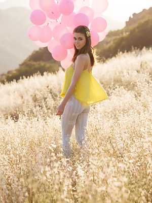 Amberleigh West is running naked in a meadow with a bunch of balloons