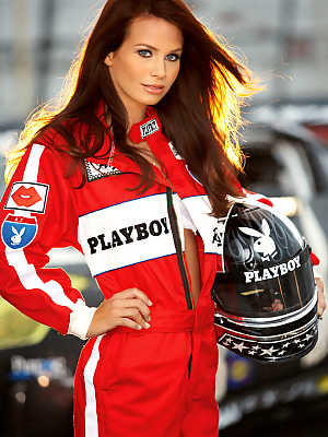 Lovely redhead model doll showing her stunning body by the racing car