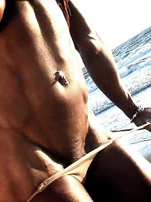 Bodybuilder Alexis Ellis shows her six pack and pierced nipples on the beach