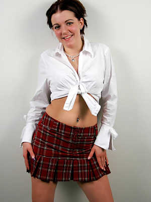 Shy and horny schoolgirl Alicia Avery posing against the wall in short skirt