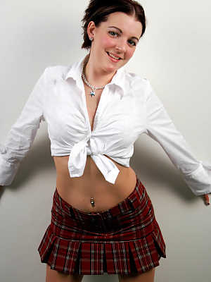 Shy and horny schoolgirl Alicia Avery posing against the wall in short skirt