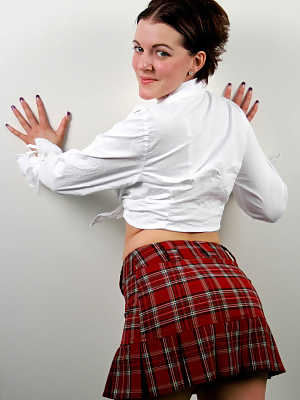 Shy and horny schoolgirl Alicia Avery posing against the wall in short skirt