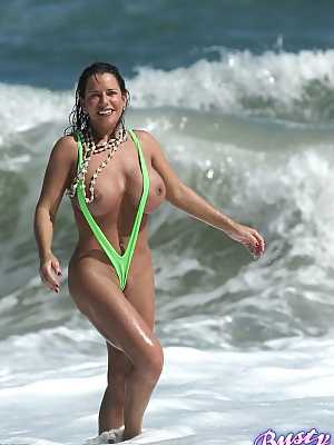 Amply endowed female Alicia Dimarco struts in a v-bikini amid foamy surf