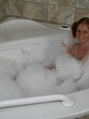 Young looking redhead Alyssa Hart jerks off her stepfather in the bathtub