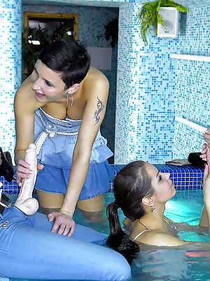 Fully clothed babes having lesbian fun with their toys in the pool