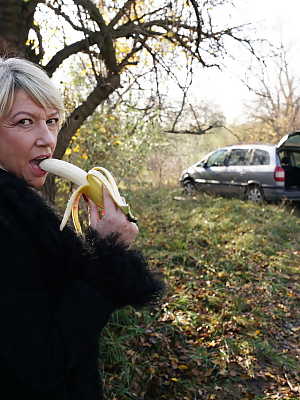 Mature blonde woman eats a banana before a gangbang in the countryside