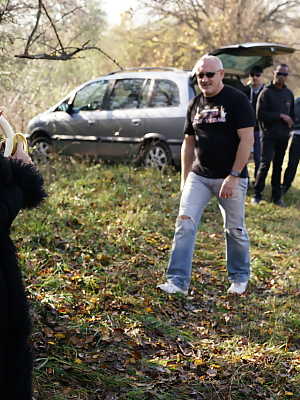 Mature blonde woman eats a banana before a gangbang in the countryside