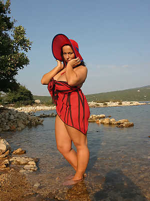 Thick female Aneta Buena shows off her large tits in the water in a hat