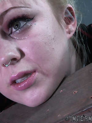 Blonde girl Anna Tyler grimaces in pain while being tortured in a dungeon