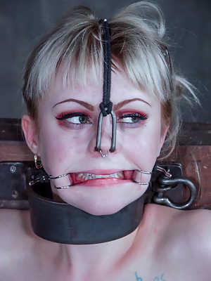 Blonde girl Anna Tyler grimaces in pain while being tortured in a dungeon