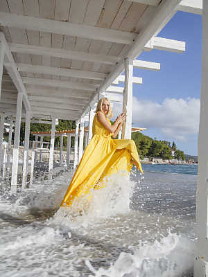 Blonde hottie Milena Angel shows her big tits under a dock in a yellow dress