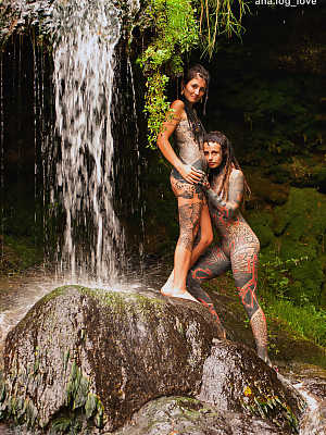 Heavily tattooed lesbians hold each other while totally naked on a bridge