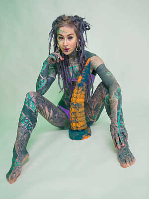 Heavily tattooed girl Anuskatzz holds a couple of taintacle toys in the nude