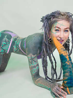 Heavily tattooed girl Anuskatzz holds a couple of taintacle toys in the nude