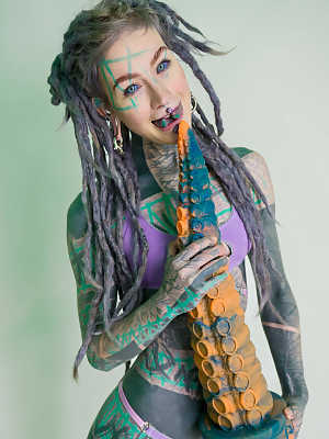 Heavily tattooed girl Anuskatzz holds a couple of taintacle toys in the nude