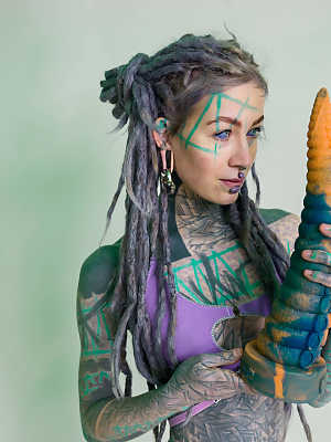 Heavily tattooed girl Anuskatzz holds a couple of taintacle toys in the nude