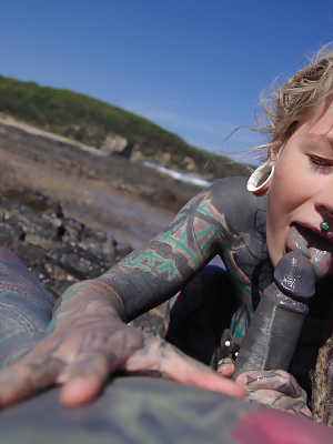 Tattooed girl jerks and sucks a tattooed penis near the ocean