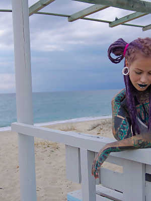 Heavily tattooed girl models a bikini in heels on a beach patio