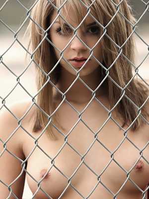 Pretty blonde Aspen Martin gets naked against a chain-link fence