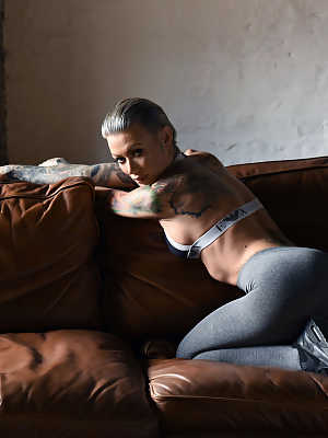 Glamorous tattooed babe Becky Holt stripping on the leather sofa