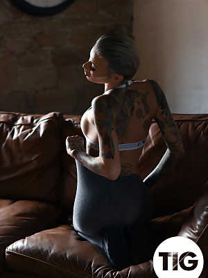 Glamorous tattooed babe Becky Holt stripping on the leather sofa