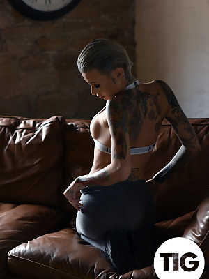 Glamorous tattooed babe Becky Holt stripping on the leather sofa