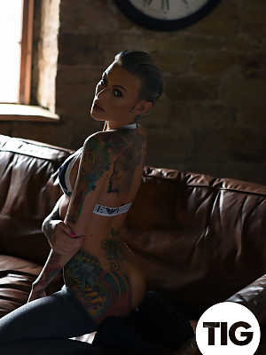 Glamorous tattooed babe Becky Holt stripping on the leather sofa