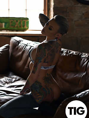 Glamorous tattooed babe Becky Holt stripping on the leather sofa