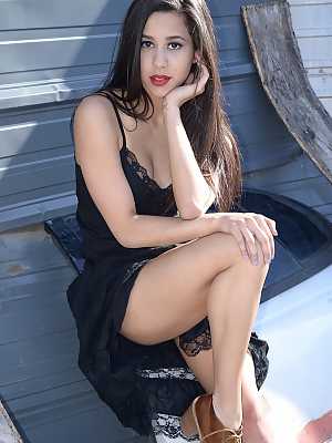 Dark haired amateur Bella Quinn models a black dress outdoors in junkyard