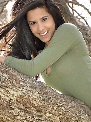 Latina chick Bella Quinn climbs a tree in the park wearing a sweater and jeans