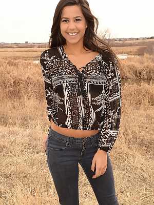 Latina girl Bella Quinn models in a field wearing a bra and jeans