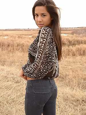 Latina girl Bella Quinn models in a field wearing a bra and jeans