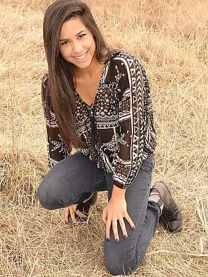 Latina girl Bella Quinn models in a field wearing a bra and jeans