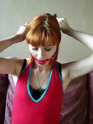 Kinky redhead affixes herself with a ball gag before tying herself up