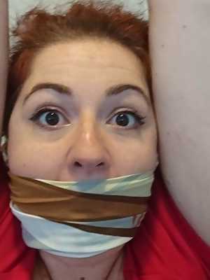 Redheaded woman is silenced with gags while restrained in her home