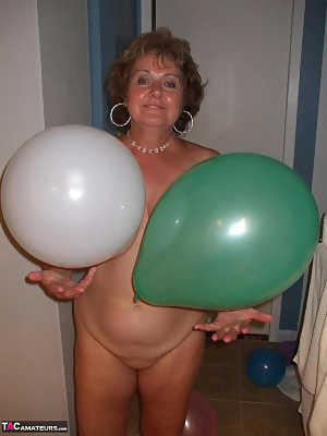 Mature lady models totally naked while playing with balloons