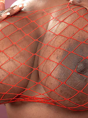 Ebony MILF Camille Morgan unveils great tits to model naked in red fishnet