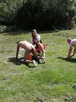 Horny femdom girls in costume head to the field to milk their naked man slave