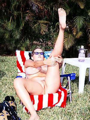 Busty Carrie Lynn spends Sunday sunbathing on the US flag at backyard