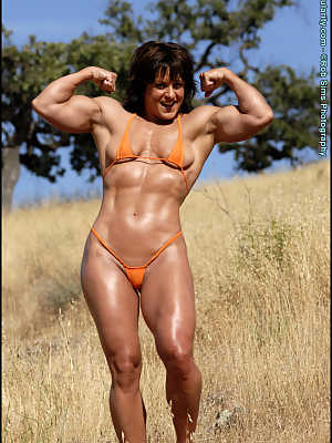 Female bodybuilder Cori Gates removes her bikini while flexing in a field