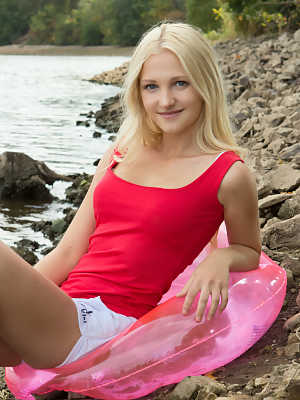 Petite blonde teen shows off her A cup tits and bald twat on rocky shoreline