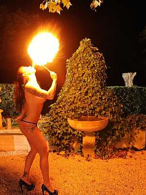Femdom Daniela gives an outdoor fire-play performance with her big boobs bared