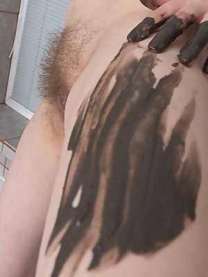 Beautiful brunette Ella Martin takes a mud bath smearing it on her hairy pussy