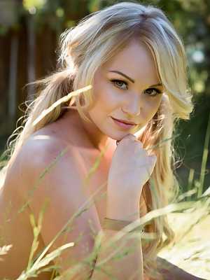 Cute blonde chick Elyse Jean models in the long grass for centerfold shoot