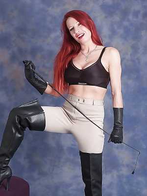 Redhead chick in riding pants and poses in leather boots and gloves