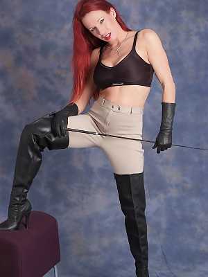 Dominant redhead Faye bares her fake tits while flexing a whip in leather wear